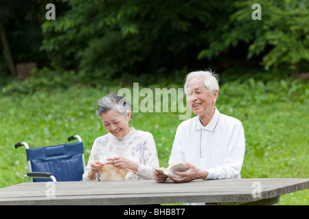 Le Japon, Tokyo Prefecture, Senior couple in park, man and woman knitting Banque D'Images