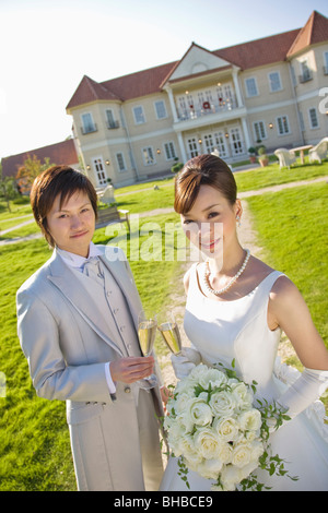 Portrait of a smiling Bride and Groom toasting champagne flute à l'extérieur Banque D'Images