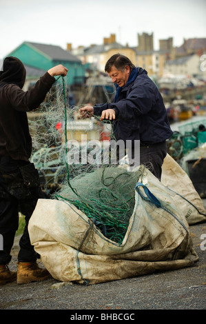 Deux pêcheurs côtiers de vérifier leurs filets de turbot au début de la saison de pêche, port d'Aberystwyth, Pays de Galles, Royaume-Uni Banque D'Images