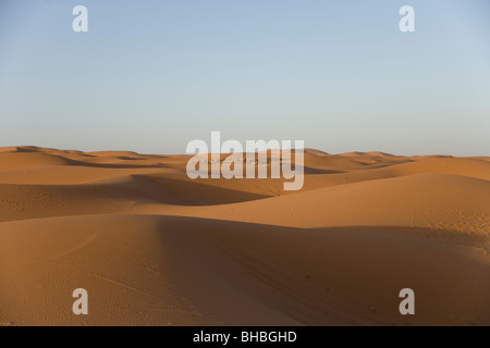 Une ligne de chameaux sur un voyage touristique au lever du soleil sur les dunes de sable de l'Erg Chebbi dans le désert du Sahara au Maroc Banque D'Images