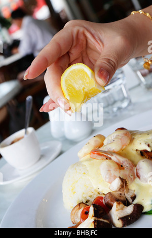 Un woman squeezing lime certains sur une assiette de légumes sautés et de fruits de mer servi avec du riz Banque D'Images