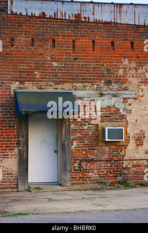 Vieux mur de briques avec auvent, porte et climatiseur de fenêtre Banque D'Images