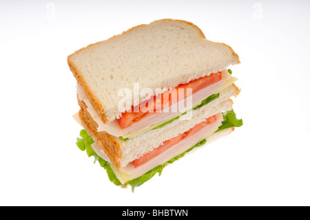 La Turquie et le fromage sandwiche réduit de moitié sur pain blanc avec de la laitue et la tomate empilées sur fond blanc. cut out. Banque D'Images