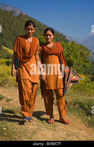 Les filles de l'école en uniforme orange à l'école à pied le long d'un sentier - AUTOUR DE MANASLU TREK, au Népal Banque D'Images