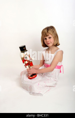 Jeune fille dans une robe de Noël blanc et des bottes tenant son Casse-noisette toy Banque D'Images