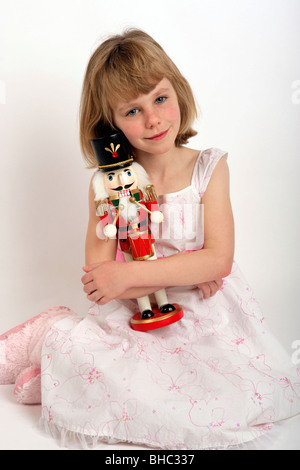 Jeune fille dans une robe de Noël blanc et des bottes tenant son Casse-noisette toy Banque D'Images