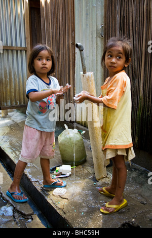 Les filles se laver à Dili le camp de personnes déplacées de l'hôpital où l'eau des toilettes et installé par Oxfam au Timor oriental Banque D'Images