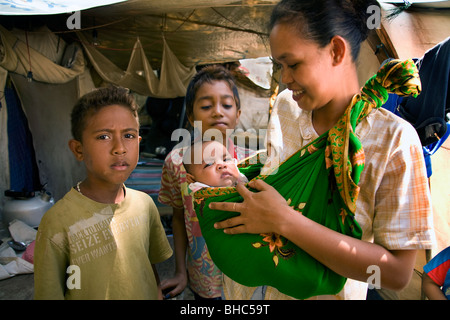 Jeune mère avec son bébé vivant dans des tentes pour personnes déplacées au camp de personnes déplacées de l'hôpital de Dili au Timor oriental Banque D'Images