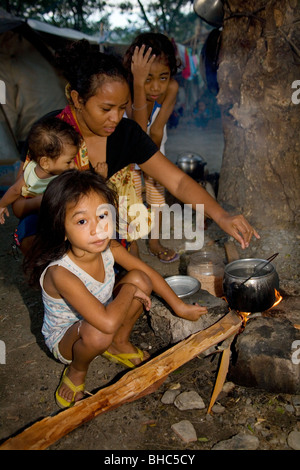 Famille avec casserole sur feu ouvert vous pourrez préparer votre petit déjeuner dans le camp pour personnes déplacées bondé de familles sans-abri à Dili au Timor oriental Banque D'Images
