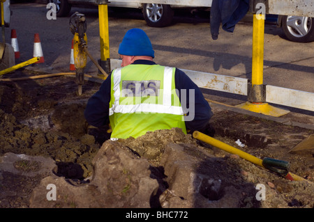 Un travailleur de creuser dans les principaux travaux de réparation à une rue résidentielle Banque D'Images