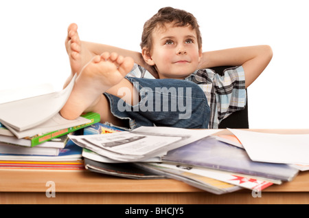 Portrait d'un écolier pieds nus avec ses pieds sur son bureau, attendant pour les vacances à venir Banque D'Images