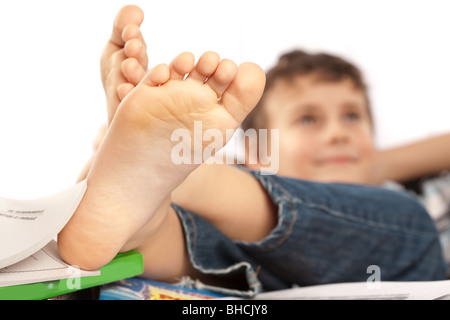 Portrait d'un écolier pieds nus avec ses pieds sur son bureau, attendant pour les vacances à venir Banque D'Images