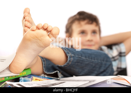 Portrait d'un écolier pieds nus avec ses pieds sur son bureau, attendant pour les vacances à venir Banque D'Images