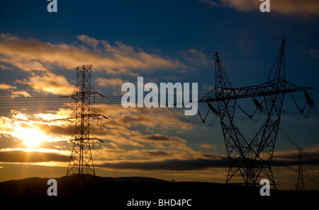 Puissance de transmission électrique haute tension lignes sont silhouetted against a sunset Banque D'Images