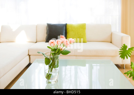 Roses dans un vase sur une table basse dans la salle de séjour Banque D'Images