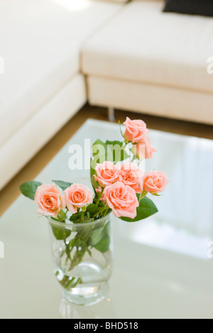 Roses dans un vase sur une table basse dans la salle de séjour Banque D'Images