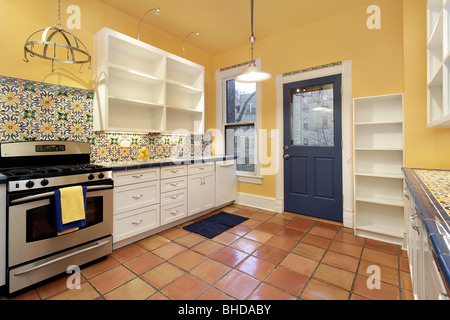 Dans la banlieue de cuisine maison avec sol en terre cuite et carreaux de murs jaunes Banque D'Images