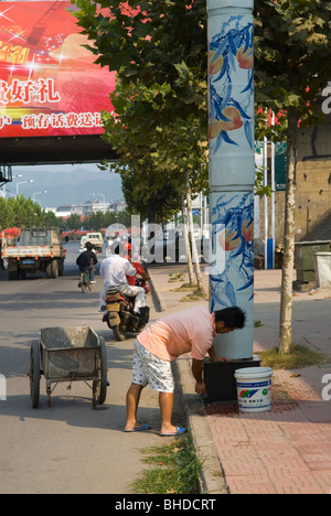 Le nettoyage d'un homme dans la lumière de la rue en céramique porcelaine 'City' Jingdezhen. La province de Jiangxi, Chine. Banque D'Images