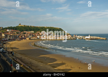 Plage à South Bay, Scarborough avec phare et entrée au port au loin. North Yorkshire Royaume-Uni. Banque D'Images