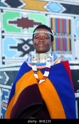 Une femme en costume traditionnel Ndebele sont devant un mur décoré de manière traditionnelle à Botshabelo village traditionnel Banque D'Images