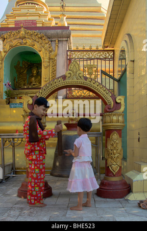 Garçon birman et son siter le cognement bell, la pagode Sule, Yangon, Rangoon, Myanmar Birmanie ; Banque D'Images