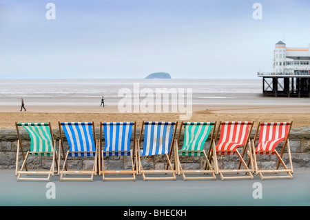 Transats au bord de la mer avec l'île de Holm mur raide sur l'horizon à Weston-Super-Mare, Somerset UK Banque D'Images