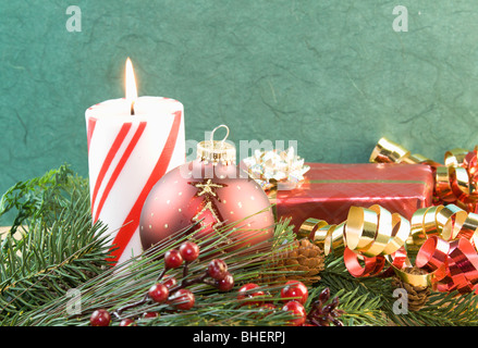 Rouge et blanc à rayures bougie de Noël avec babiole rouge, présent, et ruban frisé Banque D'Images