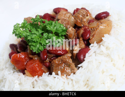 Plan Macro sur un ragoût de boeuf chili con carne avec des haricots rouges sur un lit de riz basmati blanc surmonté d'un petit bouquet de persil Banque D'Images