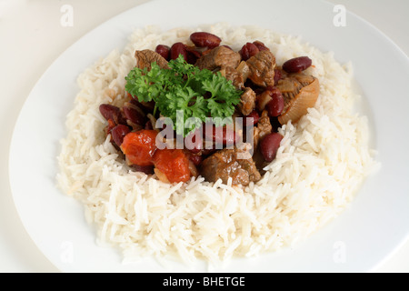 Un repas de chili con carne sur un lit de riz bouilli surmonté d'un petit bouquet de persil Banque D'Images