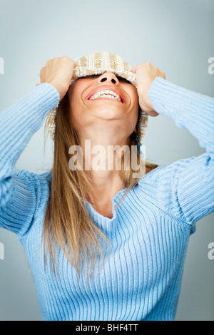 Portrait de jeune femme en riant tout en couvrant le visage avec chapeau de laine. La forme verticale, Copy space Banque D'Images
