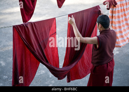 Le moine bouddhiste en mettant une robe sur la corde à linge. McLeod Ganj. Dharamsala. L'Inde Banque D'Images