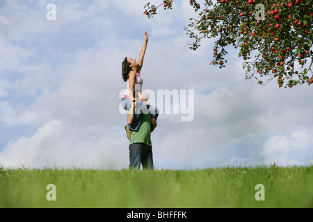 Femme sur les épaules de l'homme, pour atteindre une pomme, Styrie, Autriche Banque D'Images