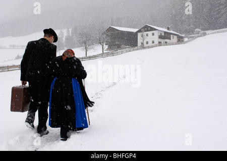 Agriculteur et sa mère marcher dans la neige en direction de l'agriculture, la ferme, le Tyrol du Sud, Italie Banque D'Images