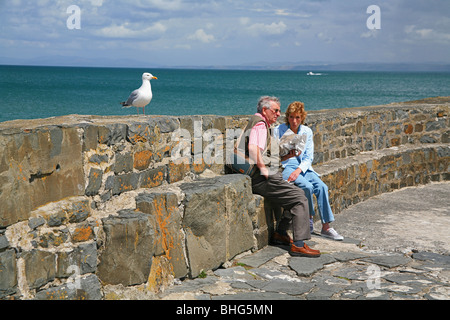 Couple assis sur le brise-lames de manger du poisson et frites à New Quay, Ceredigion, West Wales, UK Banque D'Images