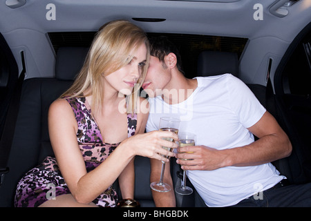 Couple drinking champagne à l'arrière d'une voiture Banque D'Images