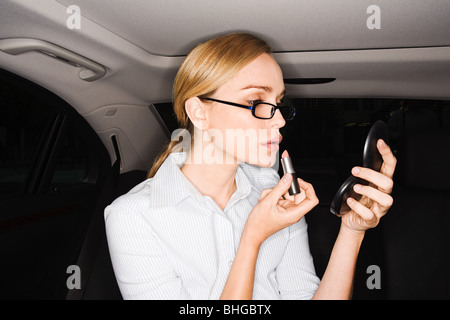 Woman applying lipstick in car Banque D'Images