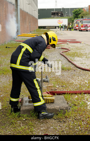 Fireman tourne sur tube à eau pour l'alimentation en eau au feu Banque D'Images