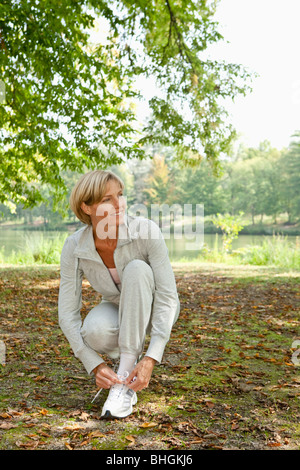 Femme d'âge moyen de lier son jogging shoe Banque D'Images
