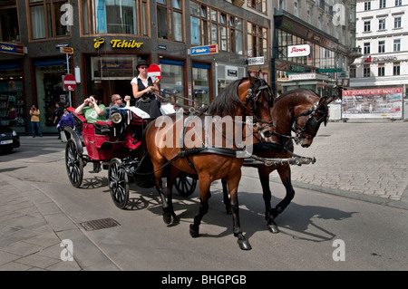 Les touristes avec des appareils photo équitation dans une calèche Fiaker viennois dans le centre de Vienne Autriche Banque D'Images