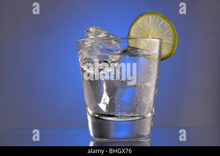 Club Soda sur les rochers à la lime slice garnir sur fond uni Banque D'Images