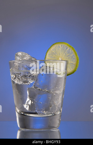 Club Soda sur les rochers à la lime slice garnir sur fond uni Banque D'Images