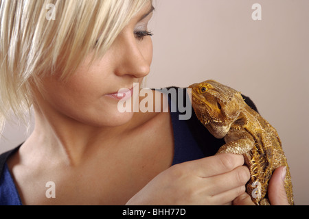 Une femme aux cheveux blonds tenant un dragon barbu dans sa main. Banque D'Images