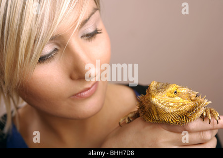 Une femme aux cheveux blonds tenant un dragon barbu dans sa main. Banque D'Images