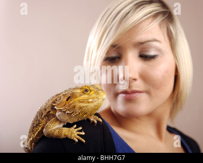 Une femme aux cheveux blonds avec un dragon barbu assis sur son épaule. Banque D'Images