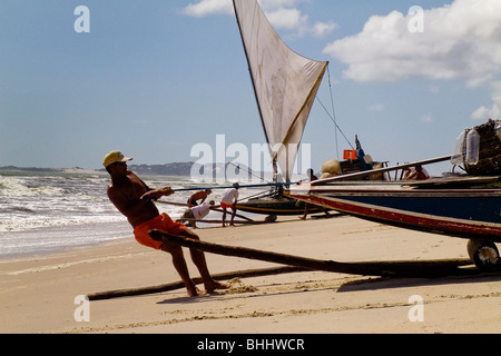 Un pêcheur brésilien pousse le bateau en bois de sciage vers l'océan sur la plage de Prainha, au Brésil. Banque D'Images