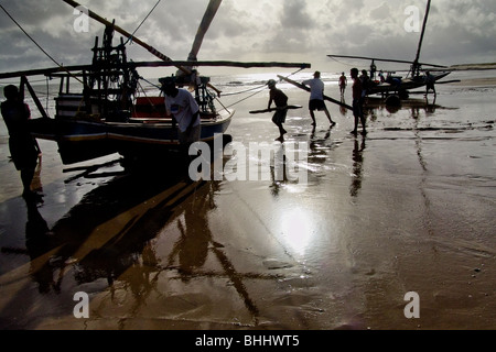 Les pêcheurs brésiliens poussant leurs mains par bateau vers l'océan pendant le lever du soleil à uruau, de l'État de Ceara, Brésil. Banque D'Images