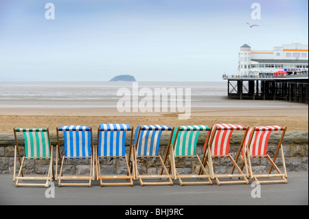 Transats au bord de la mer avec l'île de Holm mur raide sur l'horizon à Weston-Super-Mare, Somerset UK Banque D'Images