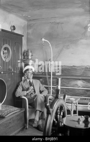 Un homme dans un chapeau de marin et bandeau ensemble se trouve dans une cabine du navire reconstruit, c1945-c1965. Artiste : SW Rawlings Banque D'Images