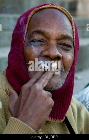 Indien à balaclava cigarette sur les rives du Gange, Varanasi, Inde Banque D'Images