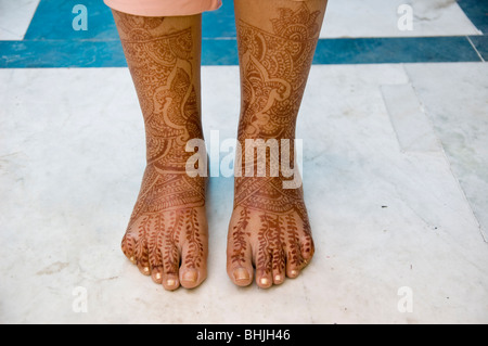 Une nouvelle épouse montre ses pieds qui sont décorées dans des tatouages au henné. Banque D'Images